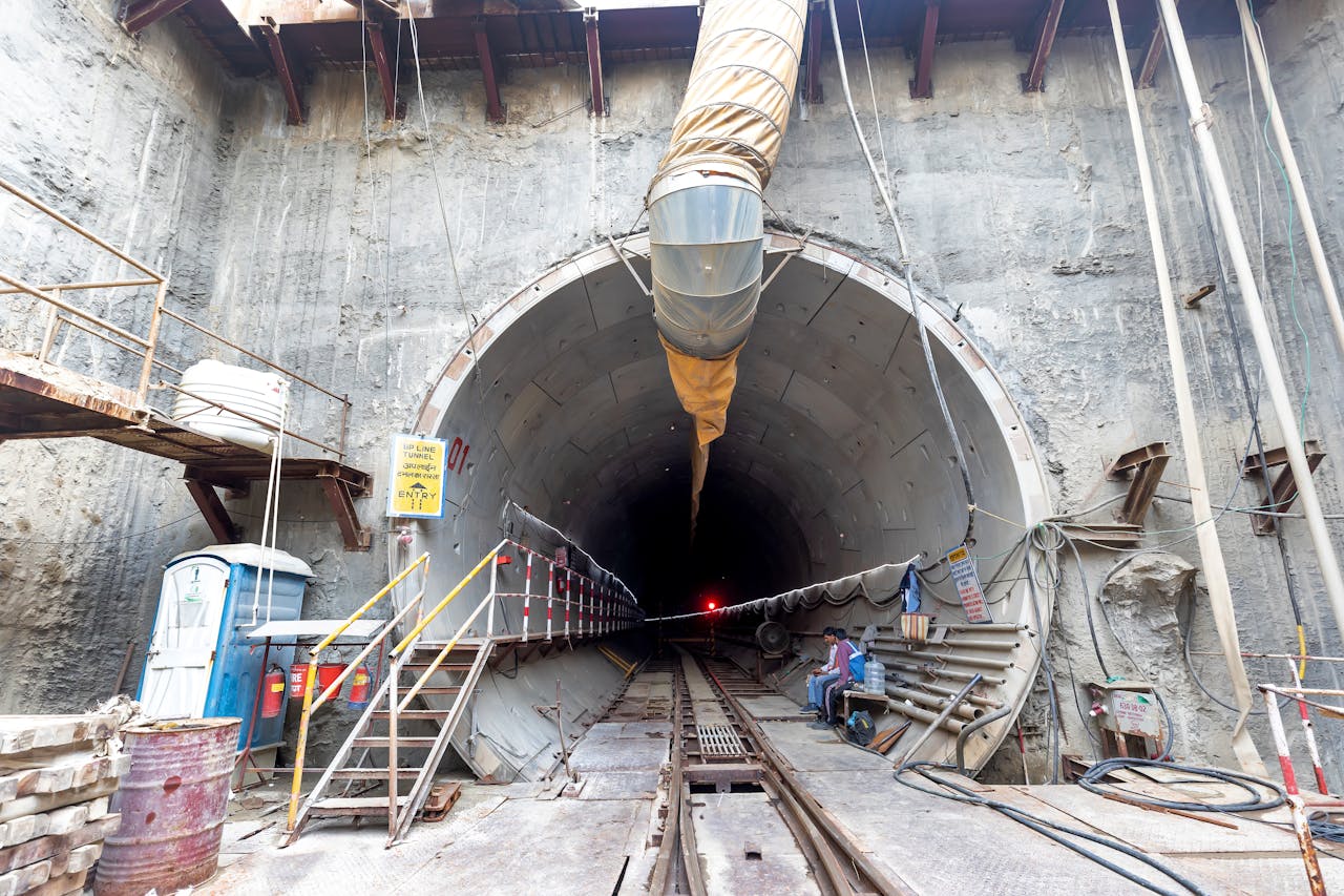 Industrial tunnel entrance under construction with heavy machinery and safety equipment.