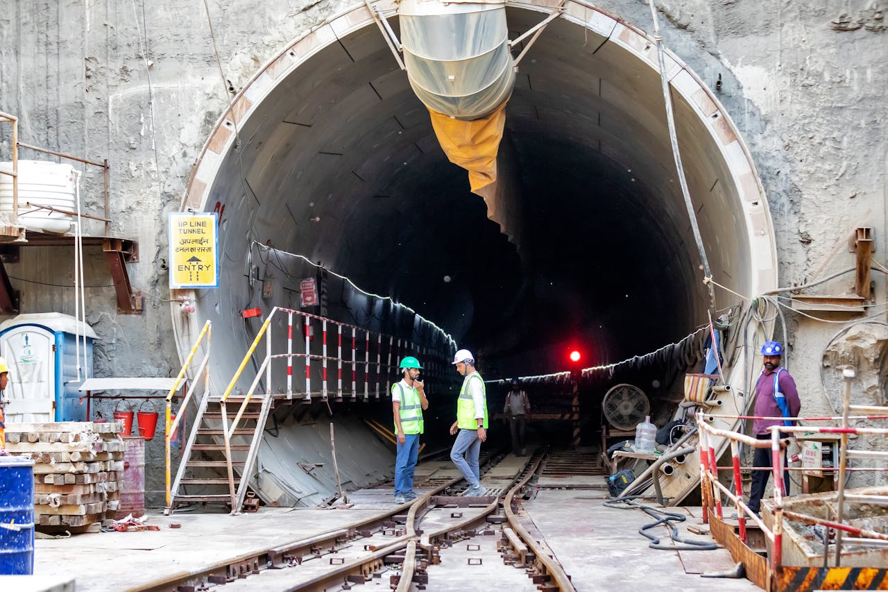 Construction workers in a tunnel. Workers in safety gear stand by a tunnel entrance.